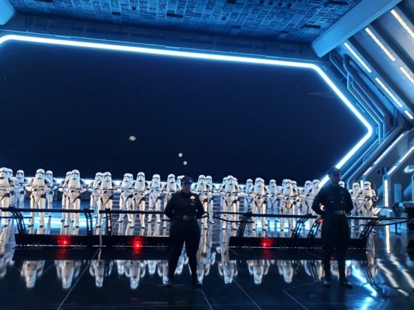 Inside the Rise of the Resistance ride at Disneyland. A row of storm trooper animatronics with Imperial Officer cast members in front of them.