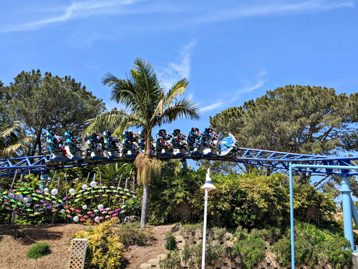Manta coaster at SeaWorld San Diego going past trees and flowers.