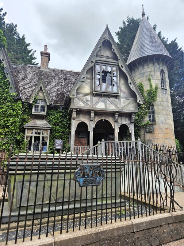 The Curse at Alton Manor exterior at Alton Towers, a dilapidated Victorian manor house with a tomb in front for Emily Alton.